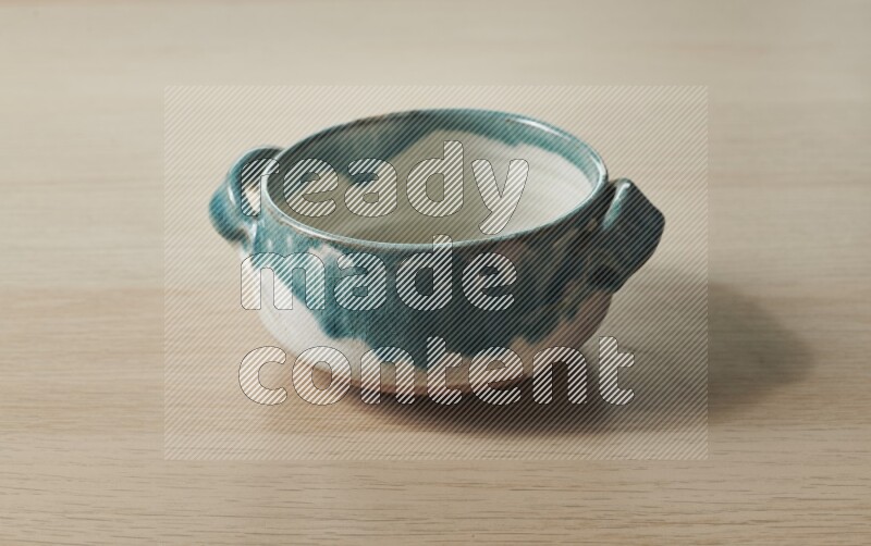 A multicolored pottery bowl on light wooden background
