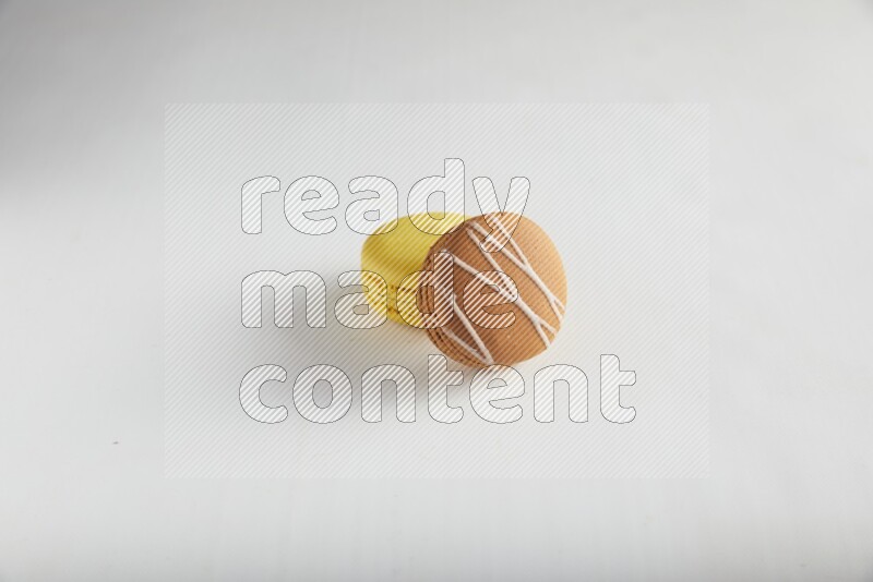 45º Shot of of two assorted Brown Irish Cream, and Yellow Lemon macarons on white background