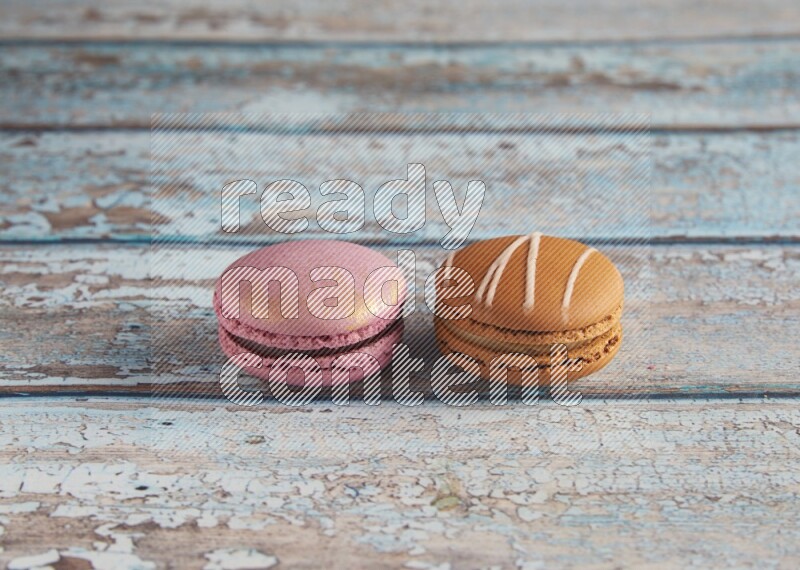 45º Shot of of two assorted Brown Irish Cream, and Purple Strawberry macarons  on light blue background