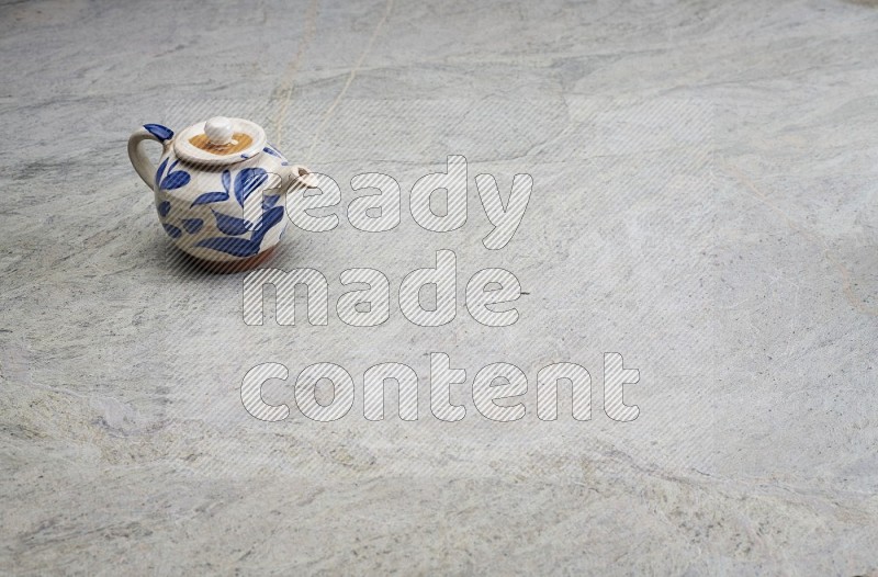 A Pottery Teapot On Grey Marble Flooring