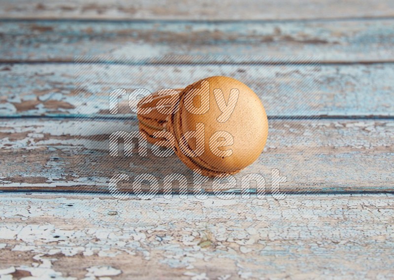 45º Shot of of two assorted Brown Irish Cream, and Brown Maple Taffy macarons  on light blue background