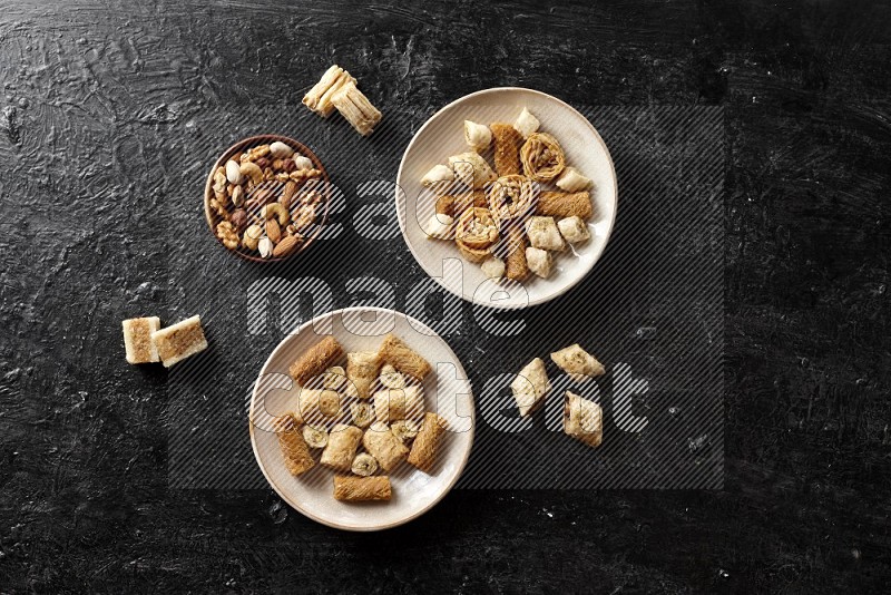 Oriental sweets in pottery plates with nuts in a dark setup