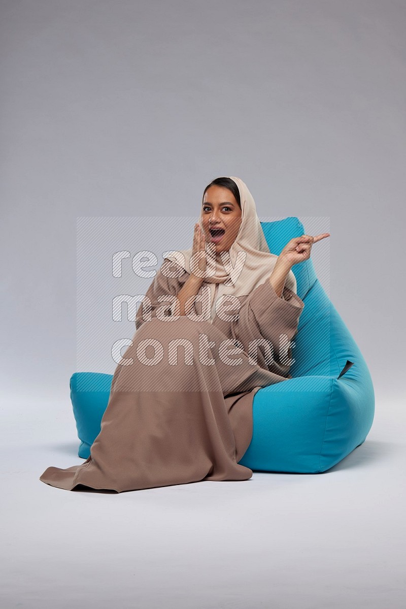 A woman sitting on a blue beanbag and interacting with the camera