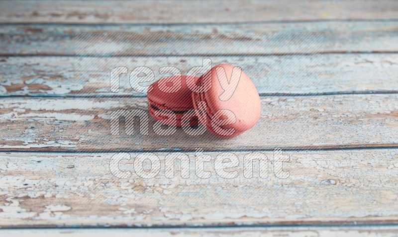45º Shot of two Pink Raspberry macarons on light blue wooden background