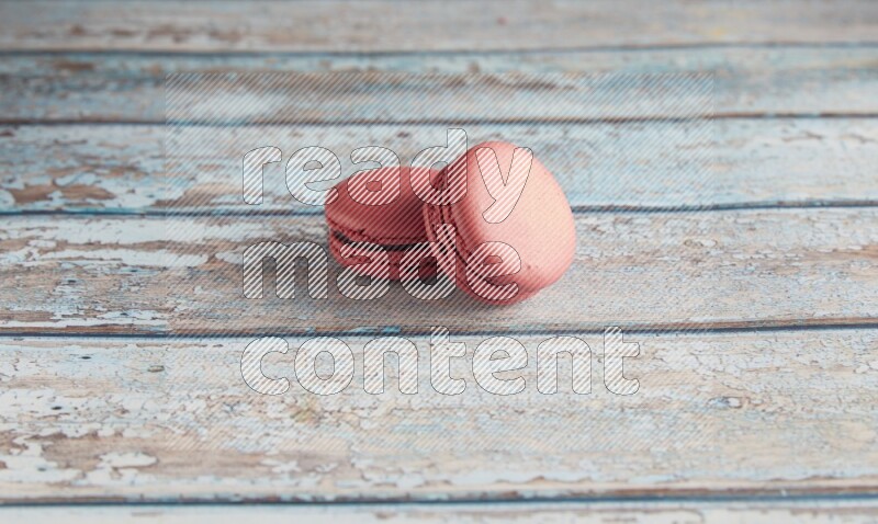 45º Shot of two Pink Raspberry macarons on light blue wooden background