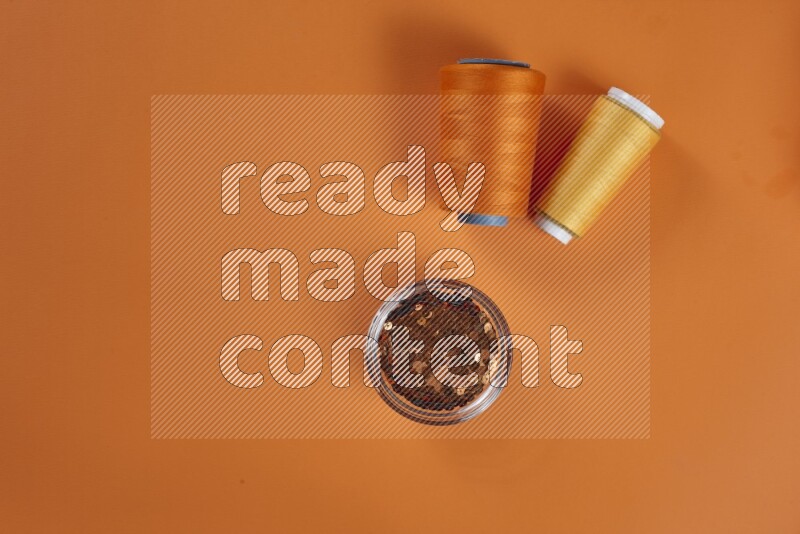 مجموعة من أدوات الخياطة والتفصيل صفراء اللون على خلفية برتقالية