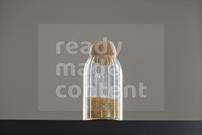 Basmati golden rice in a glass jar on black background