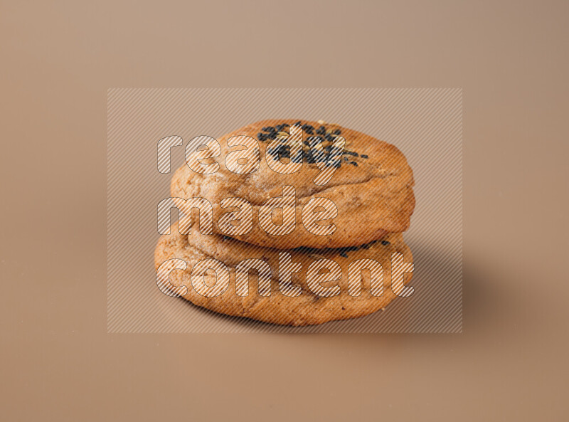 Two chocolate chip cookies on a brown background