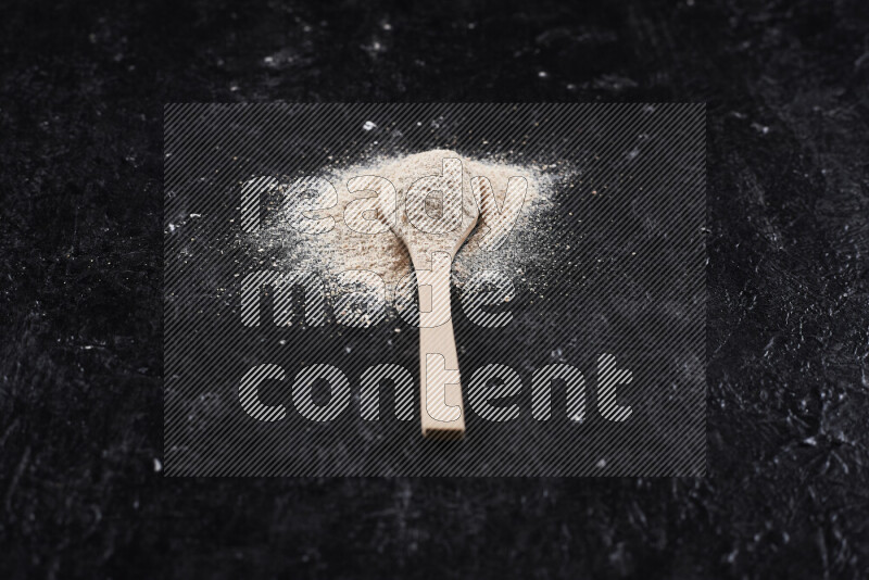 A wooden spoon full of onion powder on black background