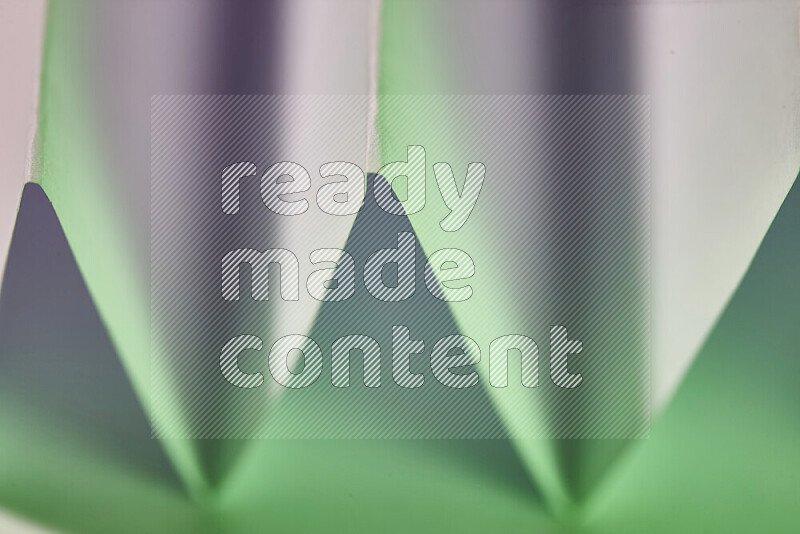 صورة مجردة مقربة تظهر طيات ورقية هندسية حادة بتدرجات اللون الأبيض و الأخضر