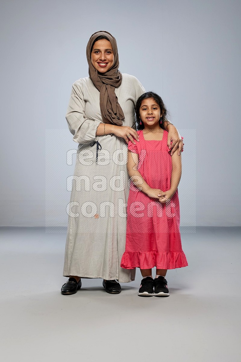 A girl and her mother interacting with the camera on gray background