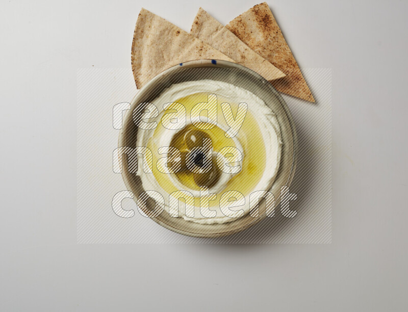 Lebnah garnished with whole olives in a grey pottery plate on a white background