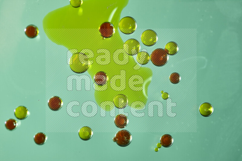 Close-ups of abstract green and red watercolor drops on oil Surface on green background