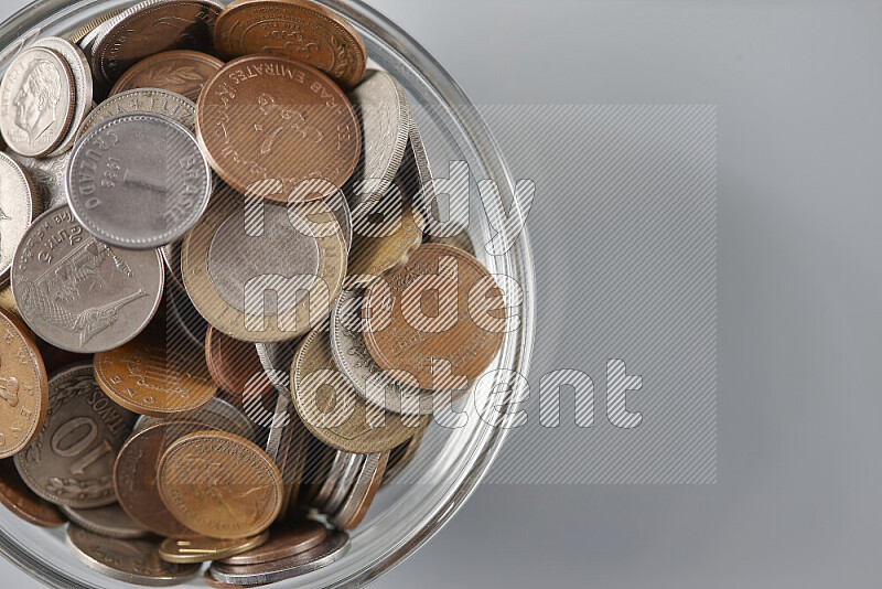 Random old coins in a glass bowl on grey background