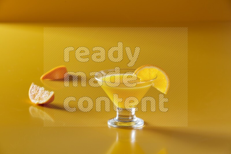 glass of orange juice with orange slice on yellow background