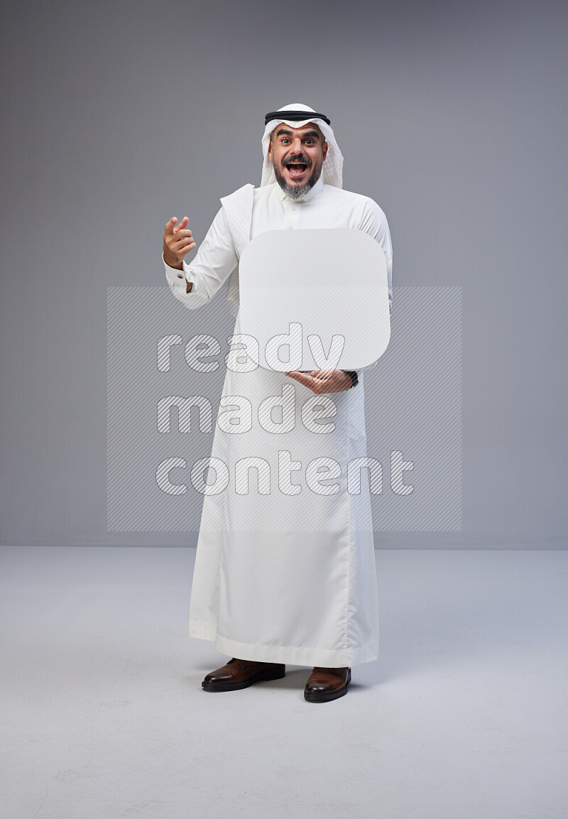 Saudi man Wearing Thob and white Shomag standing holding social media sign on Gray background