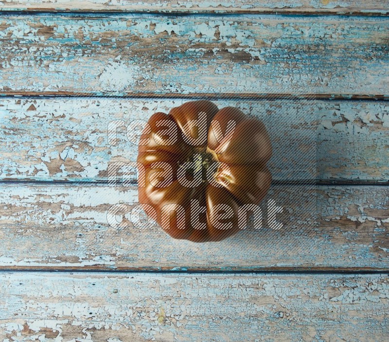 Single topview Heirloom tomato on a blue rustic wooden background