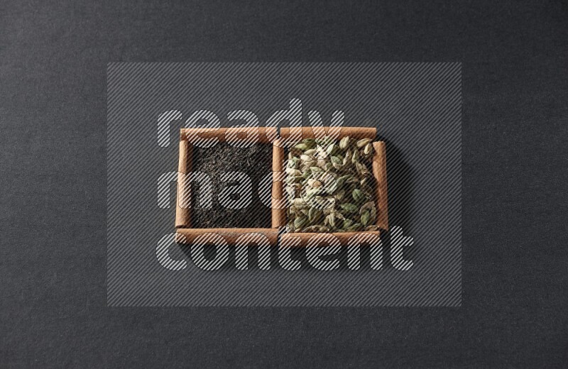 2 squares of cinnamon sticks full of cardamom and black tea on black flooring