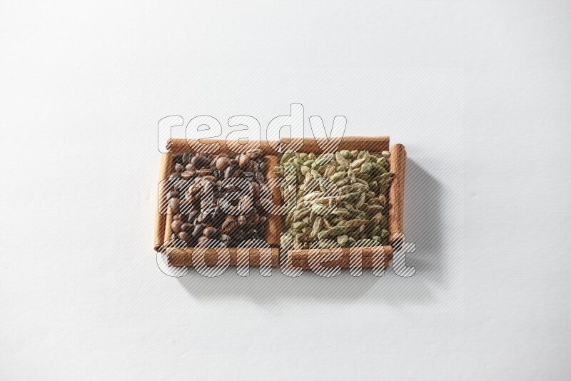 مربعان من أعواد القرفة ممتلئان بحبوب الهيل وحبوب القهوة علي خلفية بيضاء