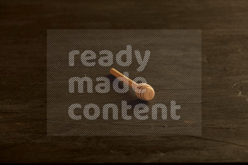 Wooden honey dipper on black slate background