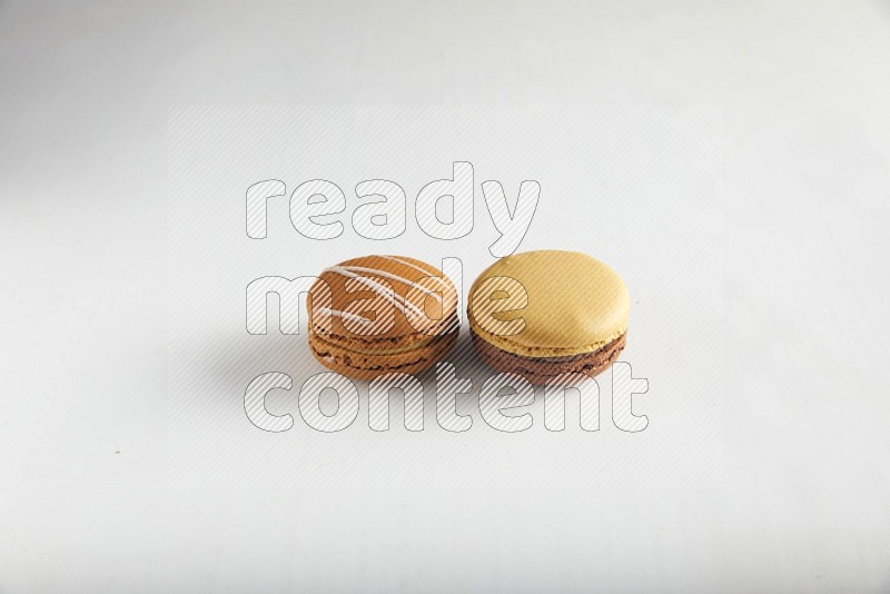 45º Shot of of two assorted Brown Irish Cream, and Yellow, and Brown Chai Latte macarons on white background