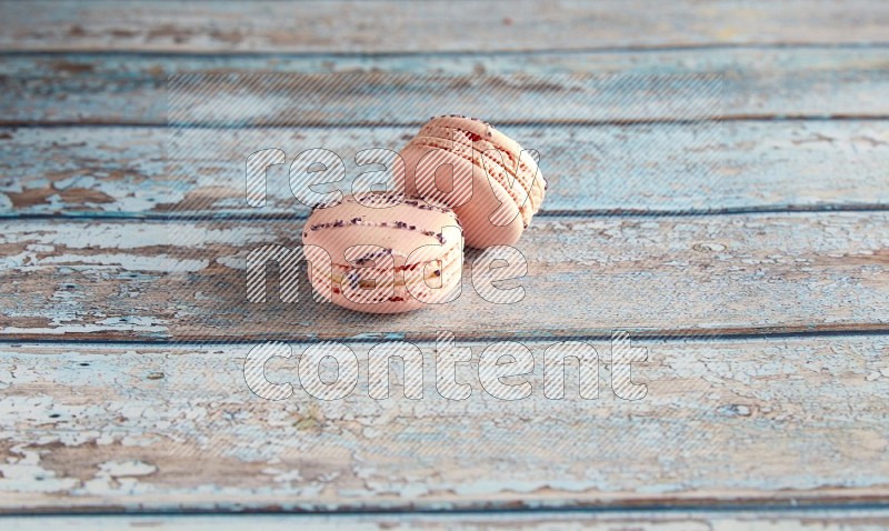 45º Shot of two pink orange blossom macarons on light blue wooden background