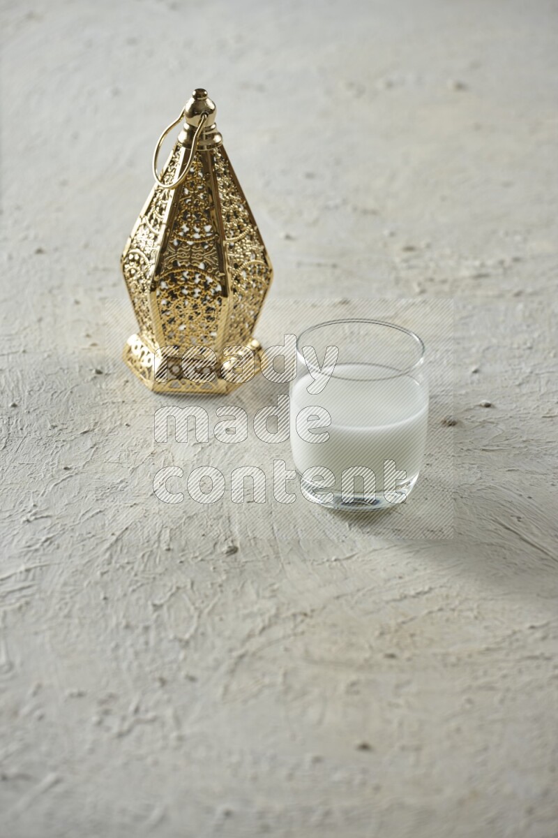 A golden lantern with different drinks, dates, nuts, prayer beads and quran on textured white background