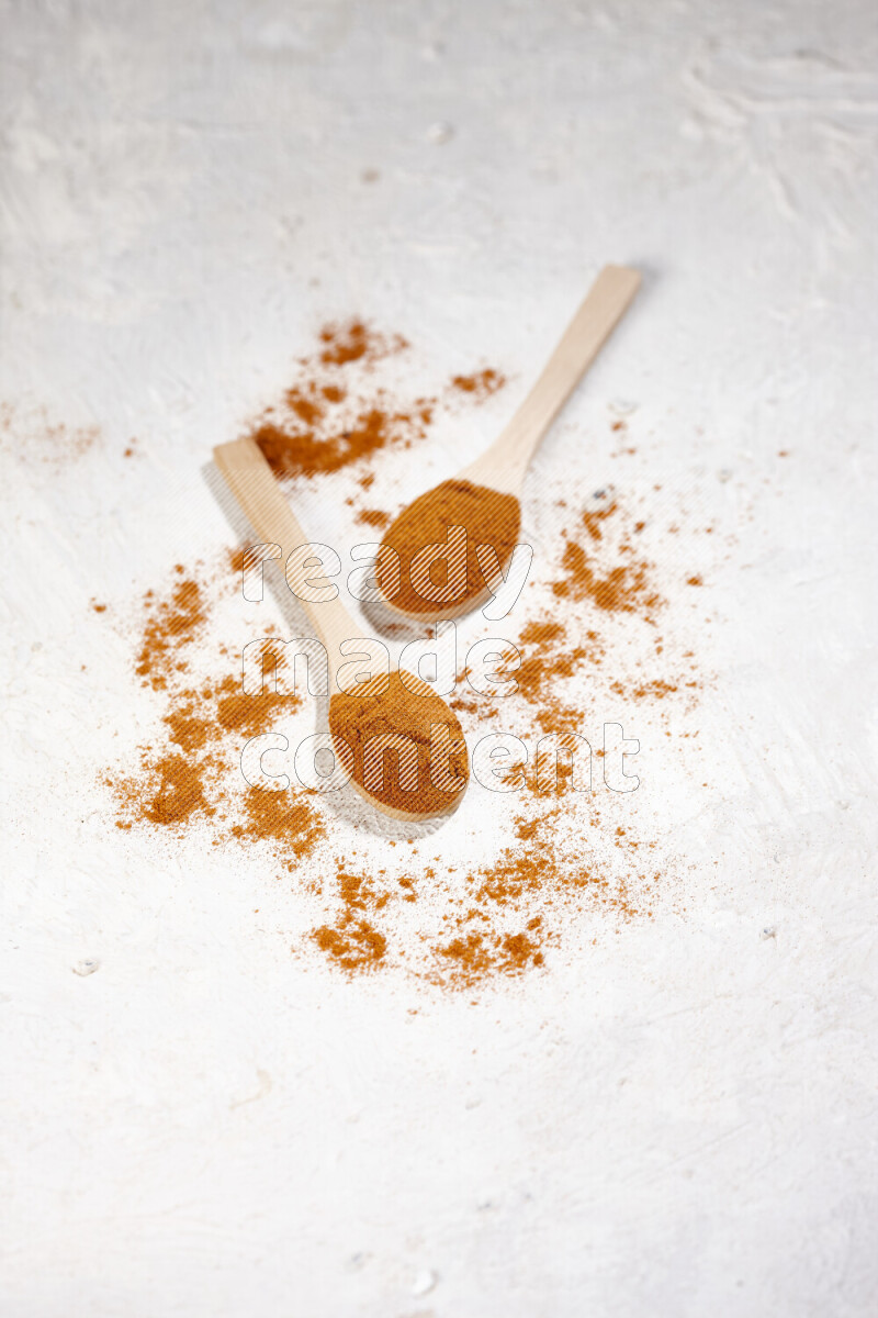 Two wooden spoons full of ground paprika powder on white background