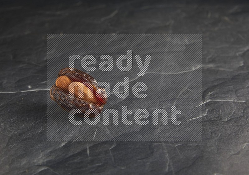 almond stuffed madjoul date on a black textured background