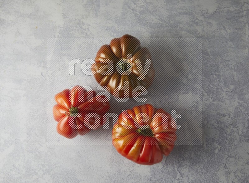 three heirloom tomatoes topview on a textured vinyl background