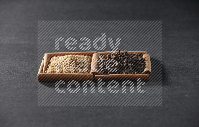 2 squares of cinnamon sticks full of sesame and cloves on black flooring