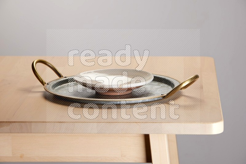 multicolored plate placed on a rounded stainless steel tray with golden handels on the edge of wooden table