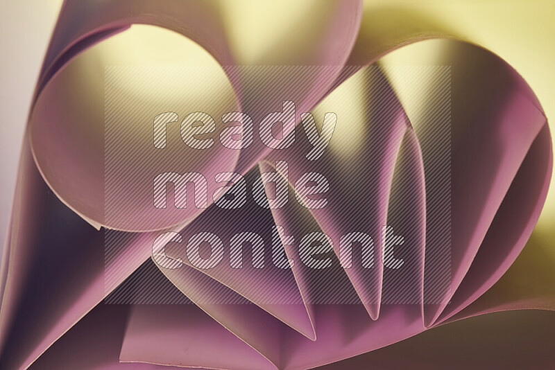 An artistic display of paper folds creating a harmonious blend of geometric shapes, highlighted by soft lighting in pink and warm tones