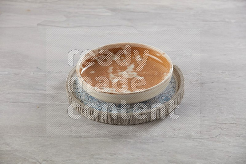 multi color pottery round dish on top of multi color round ceramic plate, on grey textured countertop