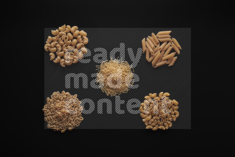 Different pasta types in bunches on black background