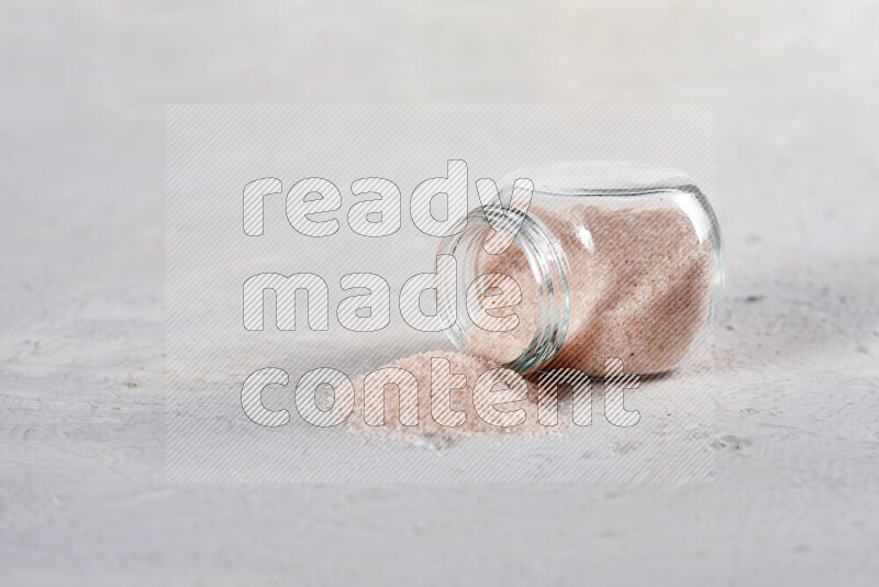 A glass jar full of fine himalayan salt on white background