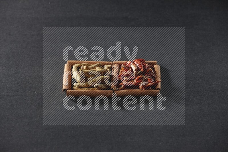 2 squares of cinnamon sticks full of chilis and turmeric fingers on black flooring