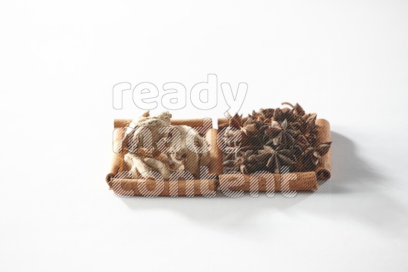 مربعان من أعواد القرفة ممتلئان باليانسون النجمي والزنجبيل المجفف علي خلفية بيضاء