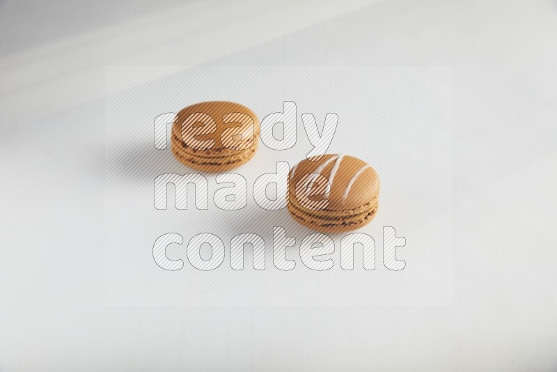 45º Shot of of two assorted Brown Irish Cream, and Brown Maple Taffy macarons  on white background