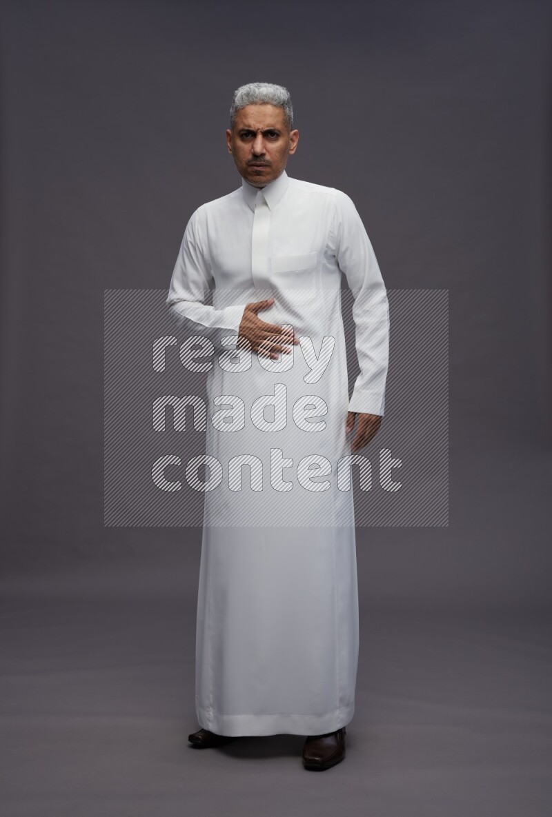 Saudi man wearing thob standing interacting with the camera on gray background