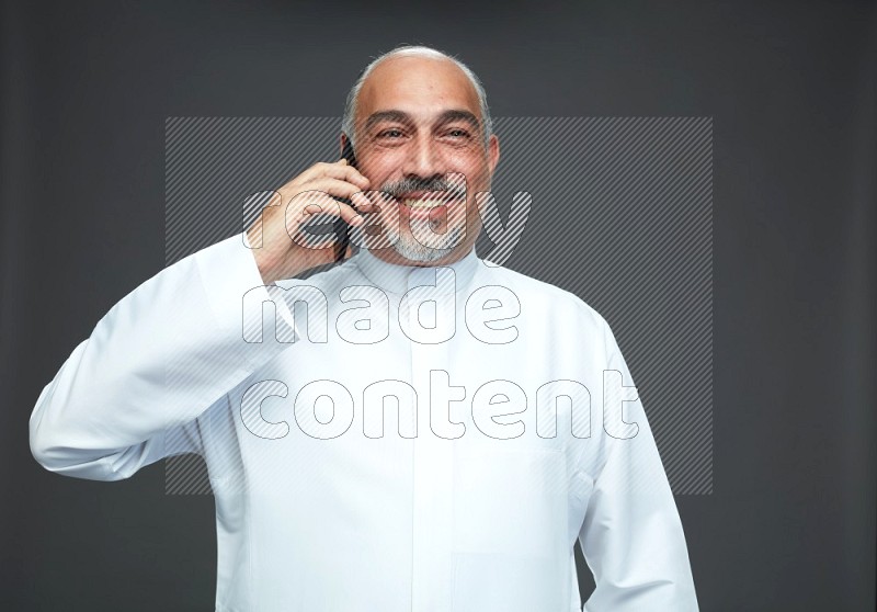 Saudi man without shomag Standing talking on phone on gray background