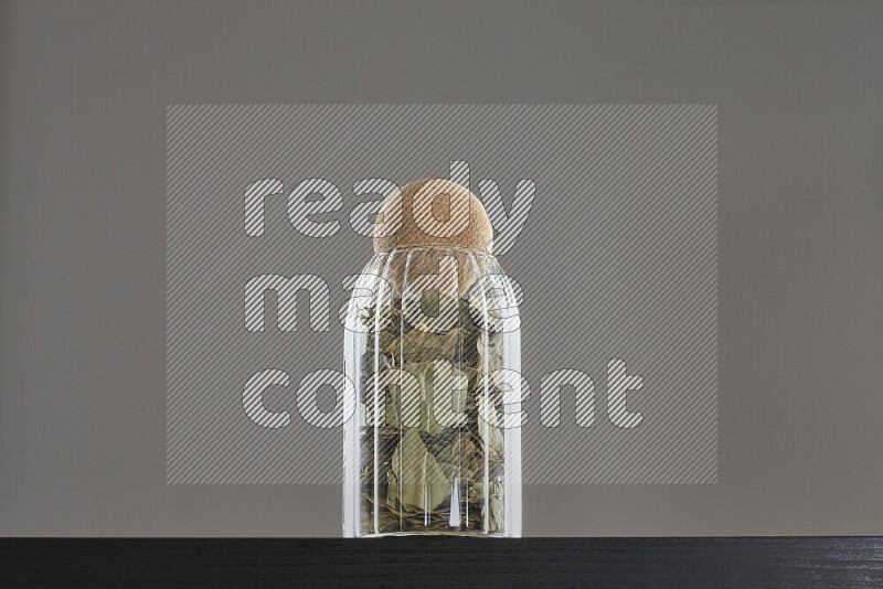 Bay laurel leaves in a glass jar on black background