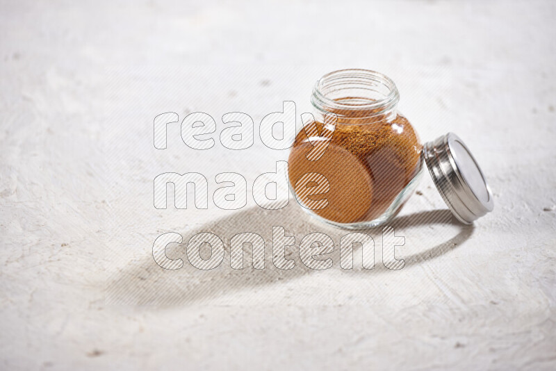 A glass jar full of ground paprika powder on white background