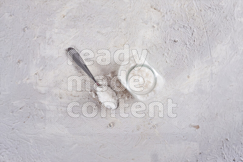 A glass jar full of coarse sea salt crystals on white background