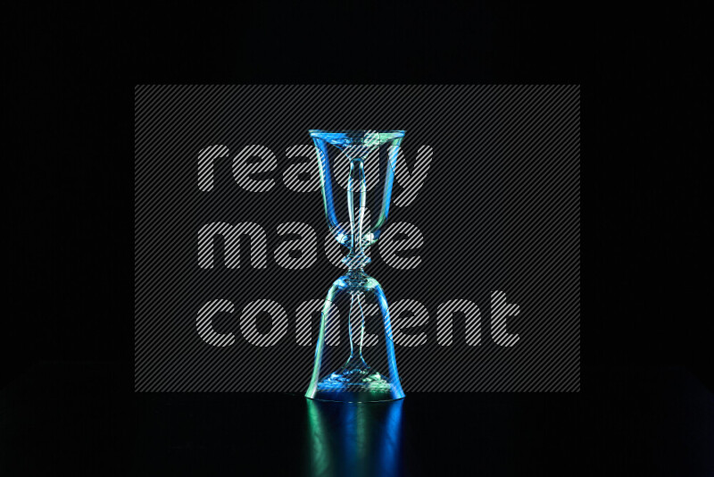 Glassware with rim light in blue and green against black background