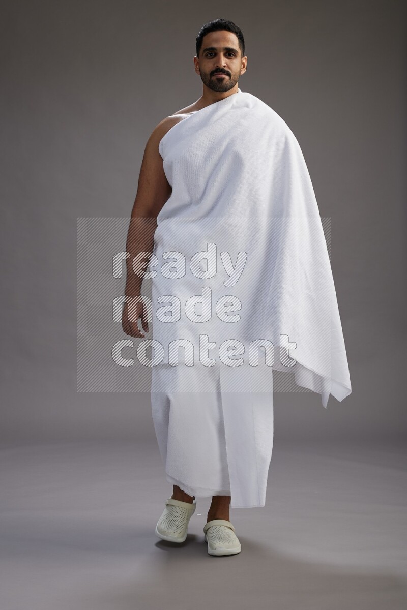 A man wearing Ehram Standing Interacting with the camera on gray background