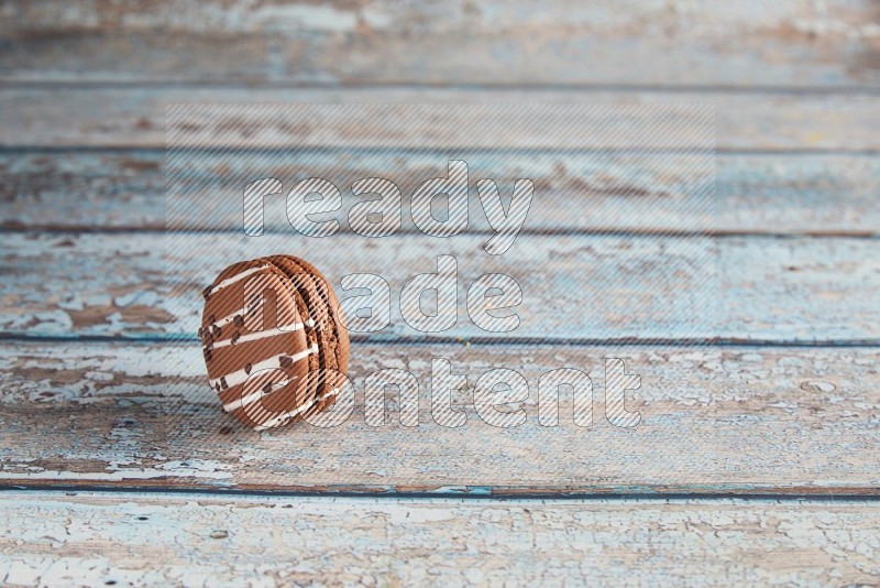 45º Shot of Brown white Chocolate Caramel macaron on light blue wooden background