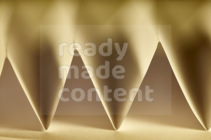 A close-up abstract image showing sharp geometric paper folds in warm gradients