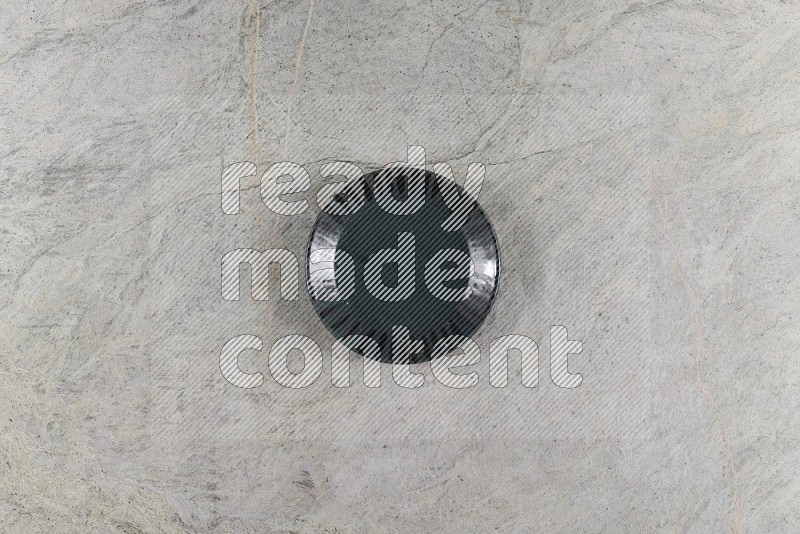 Top View Shot Of A Dark Green Pottery Plate On Grey Marble Flooring
