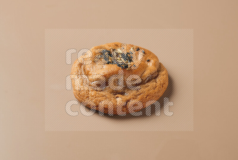 a whole Hasawi cookie with grains on a brown background